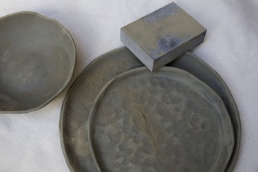 Ceramic plates and bowls being leveled with a sanding sponge.