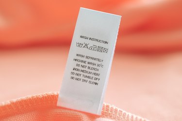 White laundry care washing instructions clothes label on pink cotton shirt