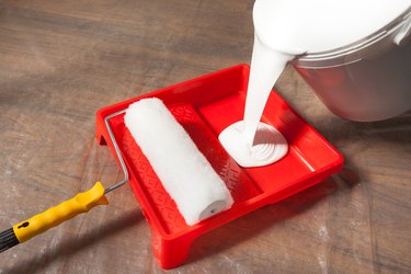 Pouring paint in a paint tray.