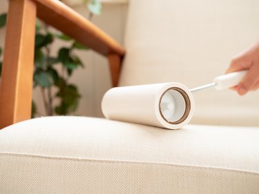 Cleaning sofa with lint roller.