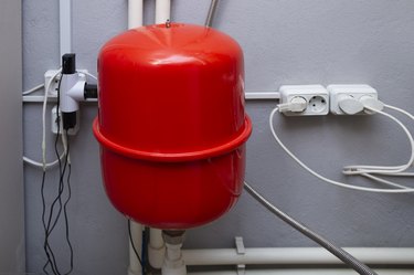 Red expansion tank and pipelines in the boiler room of a private house