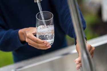 Woman's hands filling glass with water