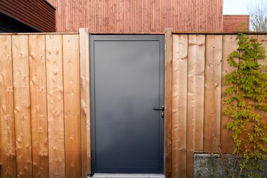 Door grey dark metal aluminum, house with wooden slats, garden access.