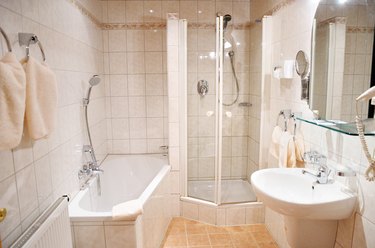 Bathroom with white bath, shower, sink, large mirror, and towels.