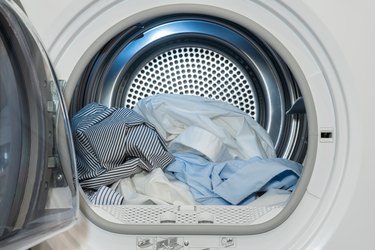Closeup view of clothes dryer with washed and dried shirts inside and door open.