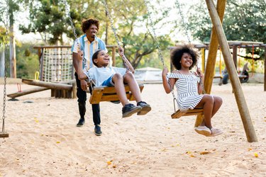 Father with daughter and son playing on swing