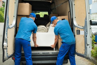 Two Workers Adjusting Sofa In Truck