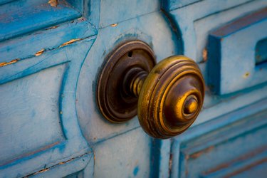 Old blue door with brass doorknob.