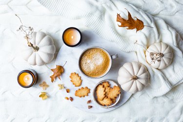 Fall cozy holiday background with cup of coffee, cookies, and pumpkins