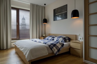 Bedroom with wooden furniture and large windows with curtains and blinds installed