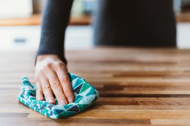 Cleaning the surface of a table with a cleaning cloth at home.