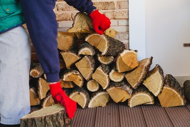 Worker in gloves hold wooden log on veranda