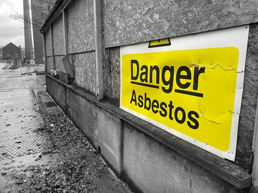 Asbestos danger sign at building construction site refurbishment of old building