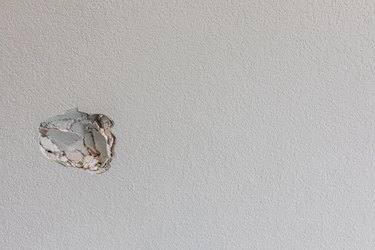 A hole in the wall of a hallways caused by a fist punching through the wall