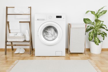Laundry room with modern washing machine and a load of white laundry.