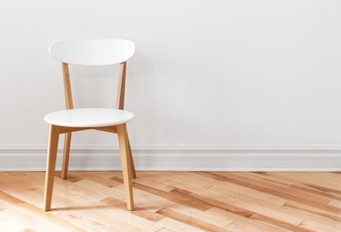 White chair, white baseboards in a white room with wood flooring.