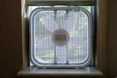 Classic window box fan inserted in home room window indoor cooling air conditioning vetilation equipment. front view hight quality close up photo