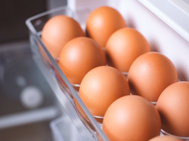 Brown chicken eggs in the egg container inside a white refrigerator.