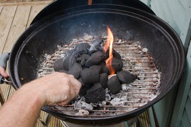 Lighting charcoal briquettes in grill.