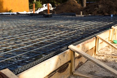 Iron fittings on wooden formwork is the basis for pouring the foundation of the house with a concrete slab.