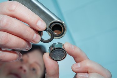 Women handyman replace tap aerator, plumber hand close-up.