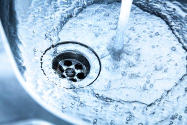 Kitchen sink with water freely running down drain.