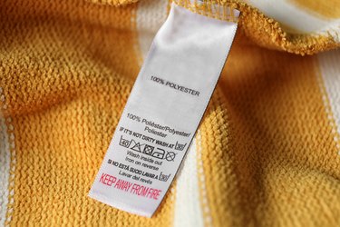 Clothing label with care symbols and material content on yellow shirt, closeup view.