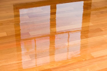 Wet polyurethane on new hardwood floor with window reflection.