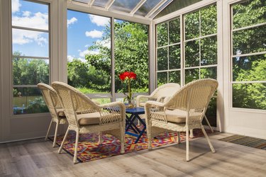 Beige wicker armchairs and blue wooden table in sunroom