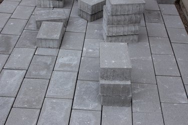 Concrete paver blocks laid beside a building, some paving stones are stacked for future use