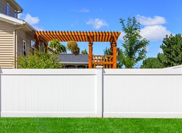 Partial view of solid white vinyl fence between yards