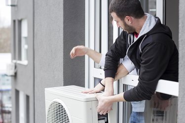 Young man installing air conditioner in an apartment