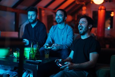 Friends shouting and cheering while playing the game battle on the playstation.