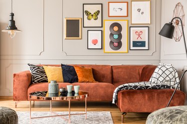 Eclectic living room interior with comfortable velvet corner sofa with pillows