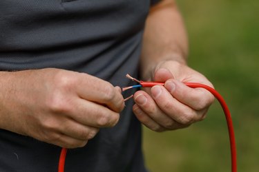 Cut electrical wires held in a mans hands