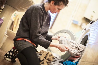 Woman removing clothes from washing machine.