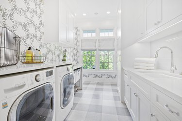 Decorative wallpaper and flooring in laundry room with new appliances.