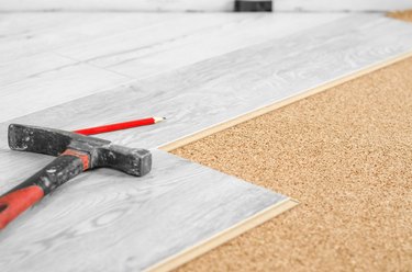 Professional laying of a floor covering - a laminate. Laying laminate on a cork base and tools