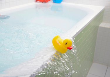 Rubber duck falling out of bath overflowing with water