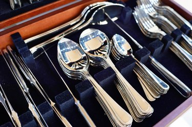 Forks, spoons, and knives in a case line with dark-blue velvet.