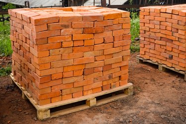 Red clay bricks are stacked on wooden pallets. Production of bricks from clay.