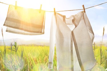 White clothes hanging backlit outdoors with sunny landscape background.