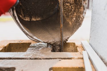 Cement slurry pouring from a bucket into the cells of a concrete block.