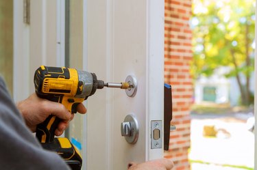 man repairing the doorknob. closeup of worker's hands installing new door locker