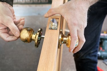 Install interior door, joiner mount knob with lock, hand close-up.