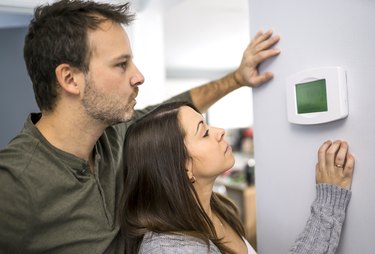 Man and woman setting home thermostat.