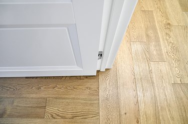 White open door in room with elegant oak parquet flooring