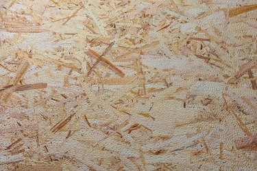 The texture of a wooden sheet of pressed sawdust with dew drops.