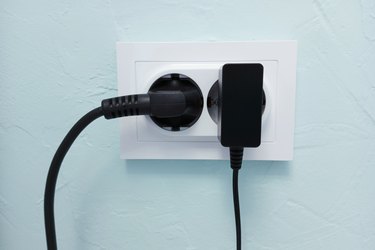 White electrical socket on  wall with electrical appliances turned on.