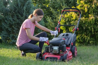 Woman checking lawn mower oil.